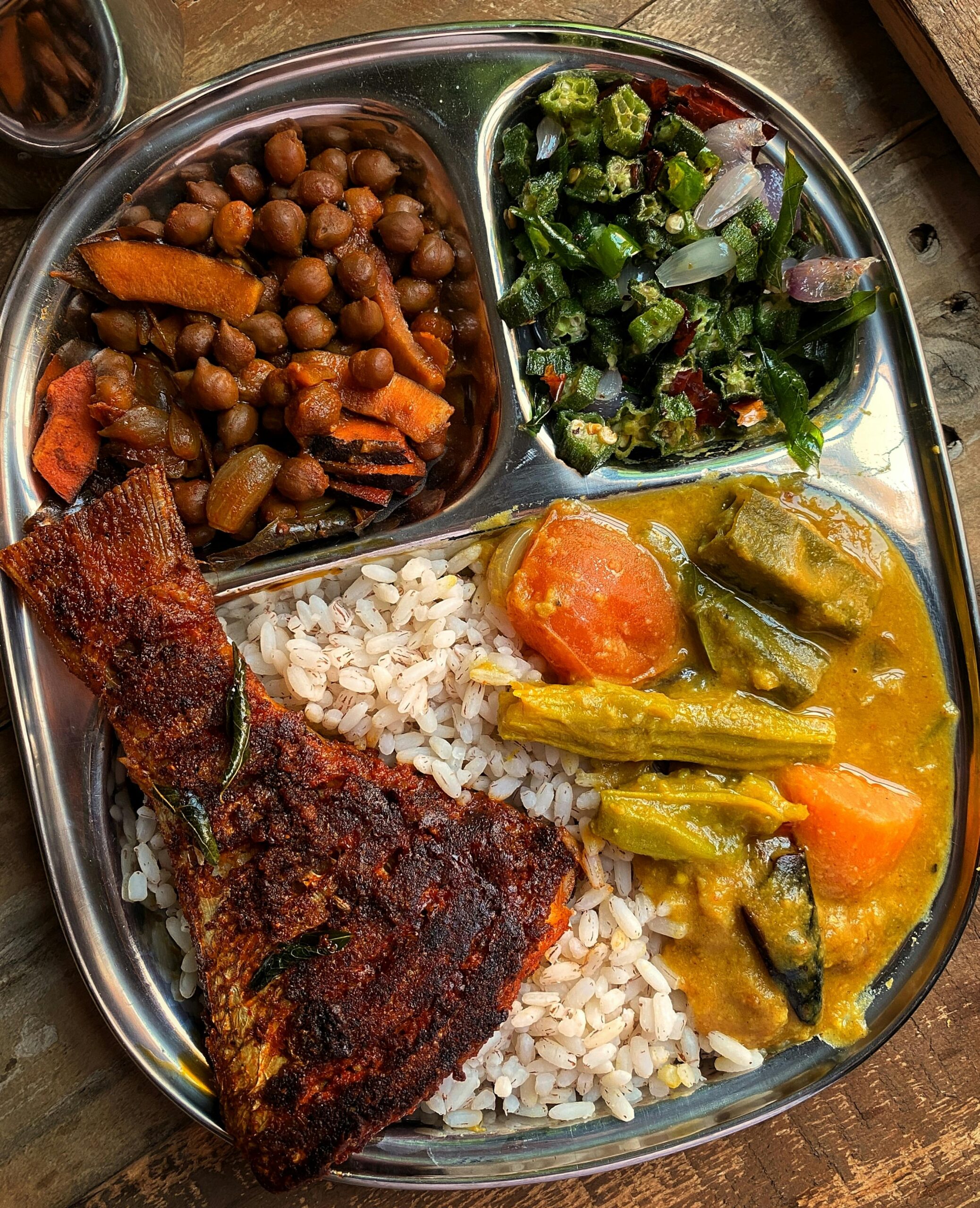 Overhead view of a colorful and aromatic Indian meal served on a stainless steel thali, showcasing authentic cuisine.